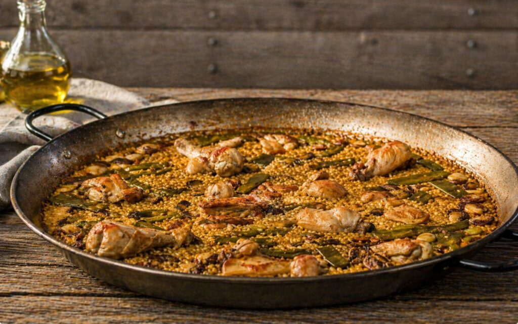 Paella Valenciana mit Hähnchen, grünen Bohnen und Garrofon Bohnen in Paellapfanne
