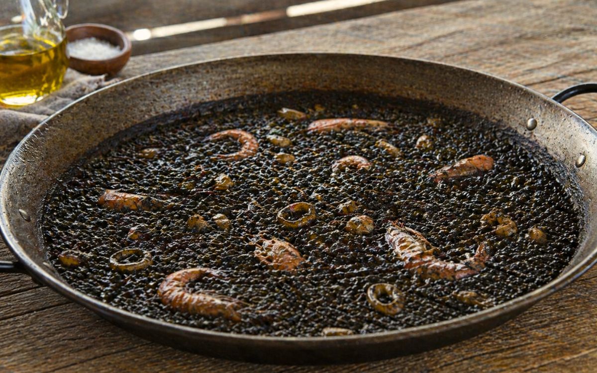 Schwarze Paella mit Garnelen und Tintenfisch (Arroz Negro) in Paellapfanne