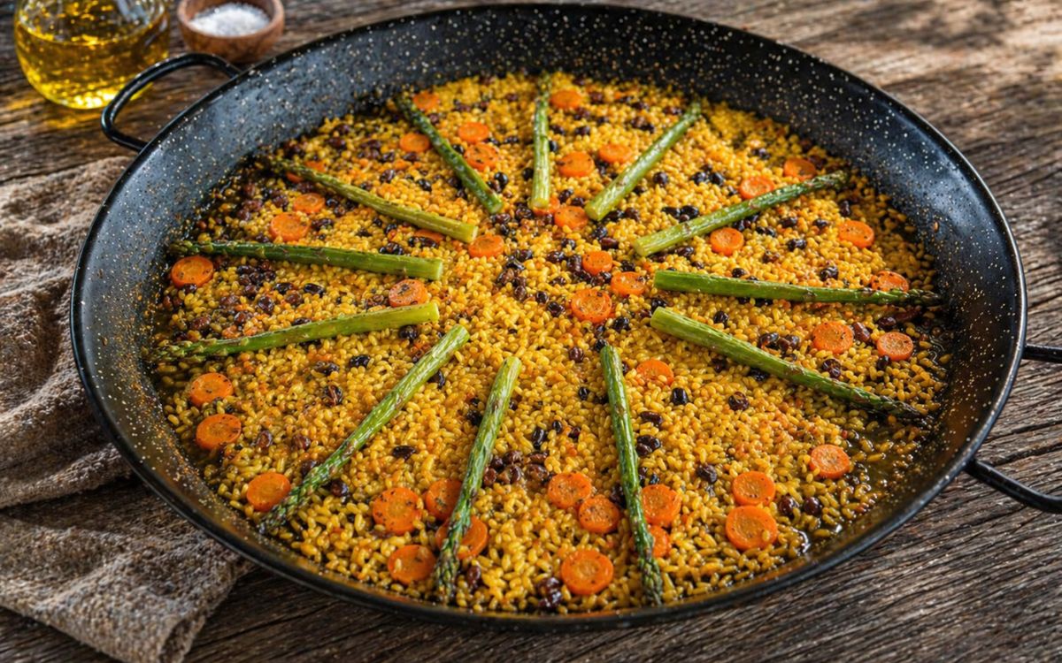 Vegetarische Paella mit grünem Spargel, Karotten und Bohnen in einer traditionellen Paellapfanne